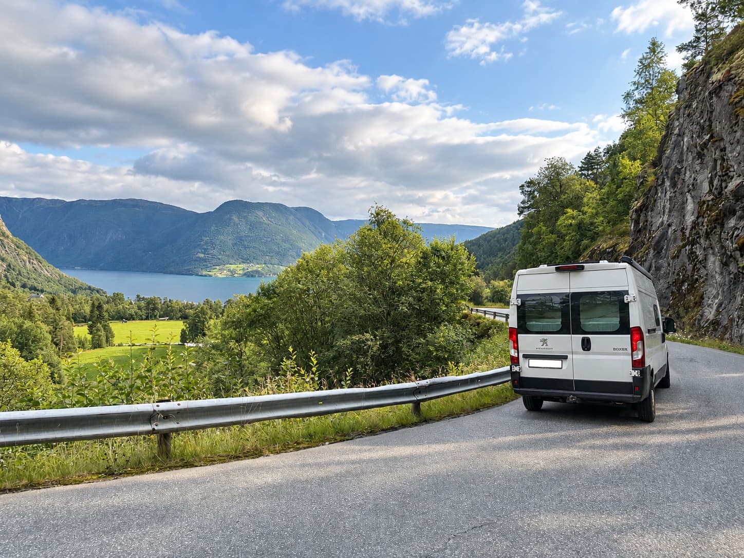 Campervan auf einer kurvigen Straße mit Blick auf Fjord und Berge