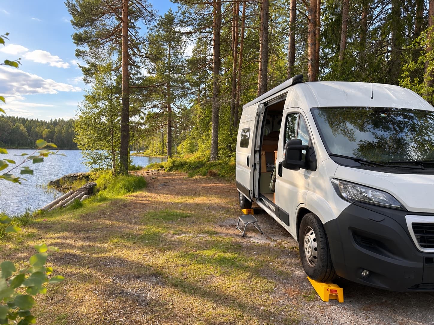 Campervan parked and levelled beside a forest lake