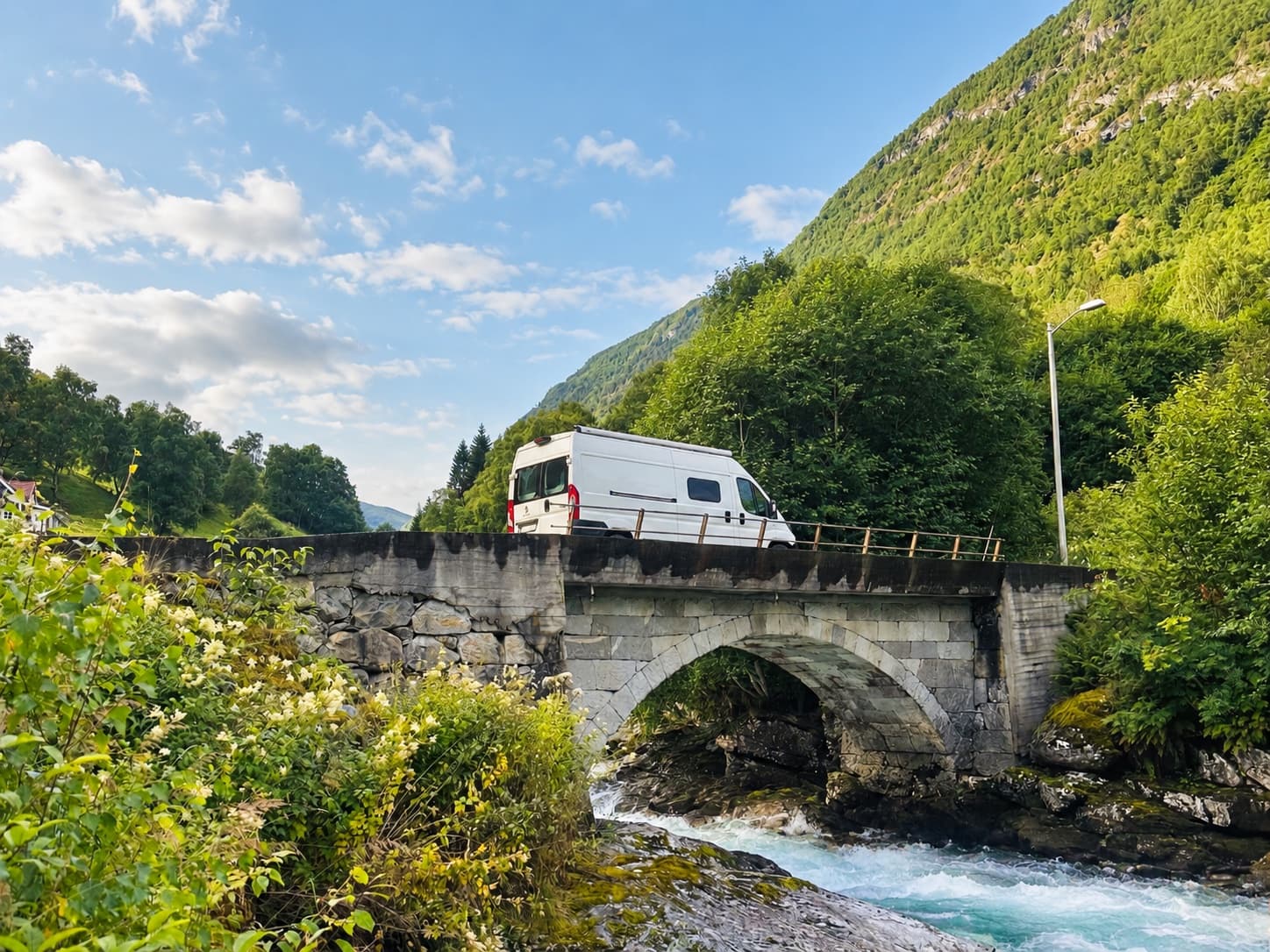 Campervan auf einer Steinbrücke über einen Gebirgsfluss