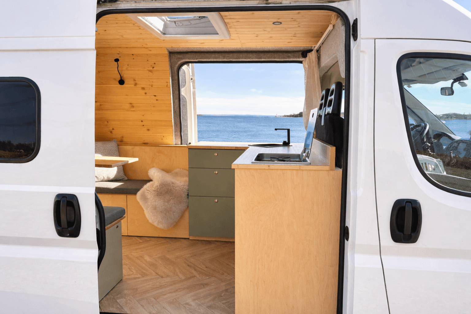 Campervan von hinten gesehen mit offener Schiebetür und Meerblick