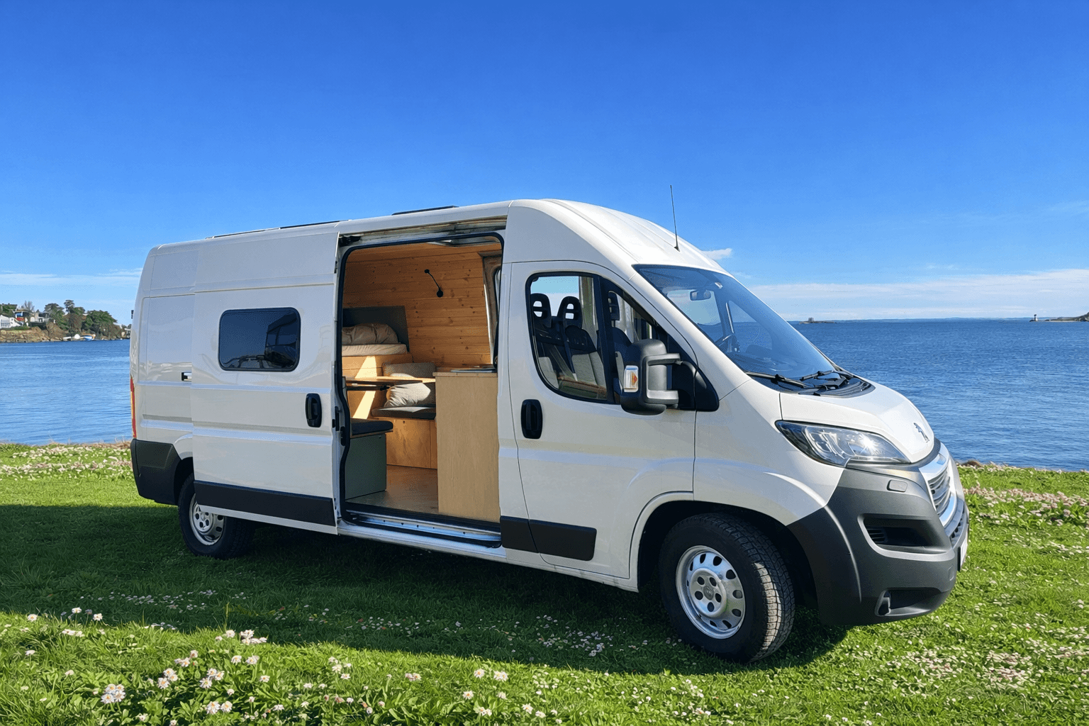 Campervan am Meer geparkt mit offener Schiebetür